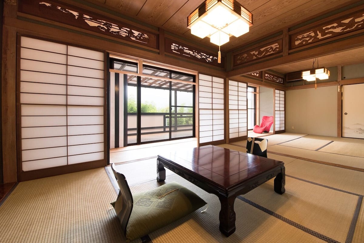 A traditional Japanese room with tatami flooring, sliding doors, and a low wooden table.