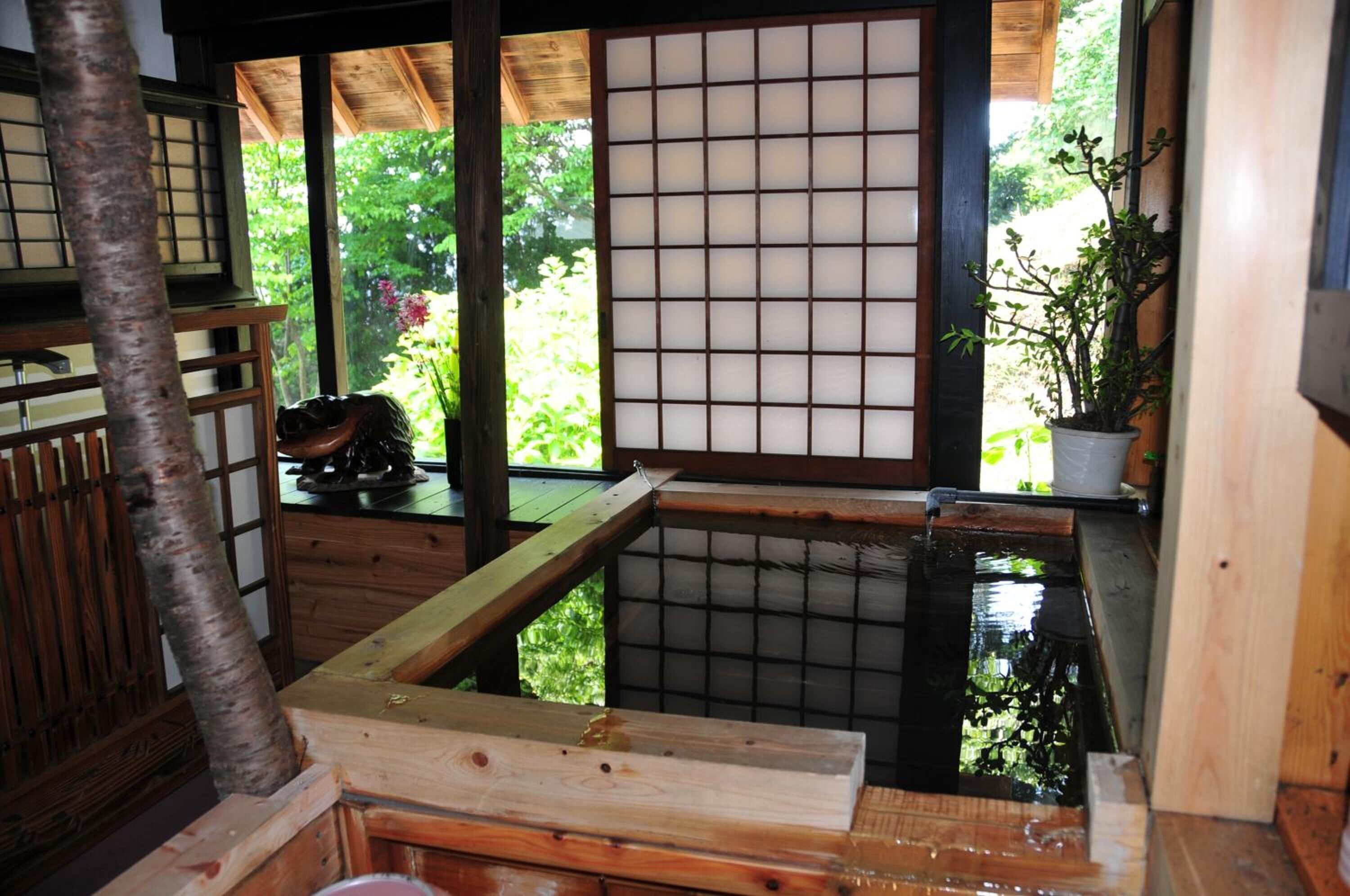 A traditional Japanese room with tatami flooring, a shoji screen, and a small water feature.