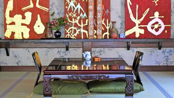 A traditional Japanese room with tatami flooring, a low wooden table, and a sofa with green cushions.