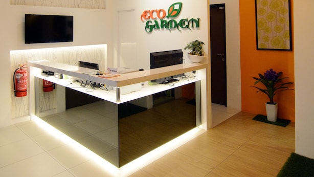 Un mostrador de recepción con un televisor de pantalla plana, un extintor y un cartel que dice "Eco Garden".