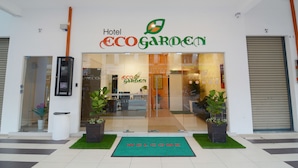 La entrada del Hotel EcoGarden, con un felpudo que dice 'Welcome' y plantas en macetas.