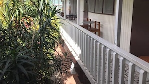 Un espace extérieur abrité, doté d’une rambarde blanche, d’une table avec des chaises et d’une porte portant le numéro 5.