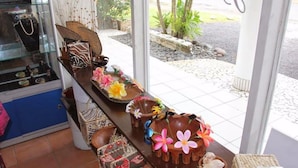 Une pièce comprenant une vitrine en verre où sont exposés des bijoux, une table en bois ornée d’objets décoratifs et une vue sur l’extérieur.