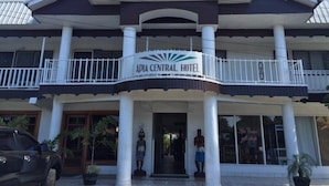 L’extérieur de l’hôtel APIA CENTRAL se distingue par son entrée imposante, un balcon et une statue placée devant.