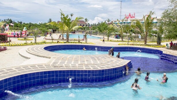 Ein Poolbereich mit mehreren Pools, Palmen und einer gefliesten Terrasse.