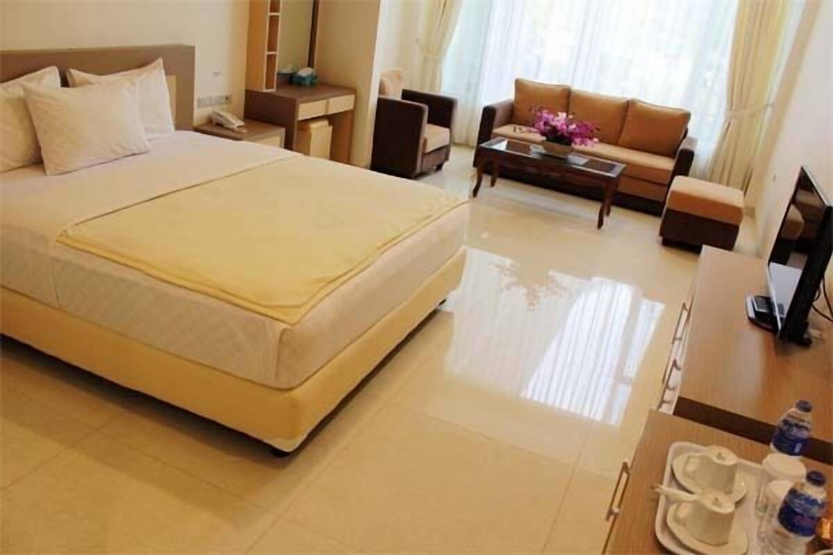 A hotel room with a bed, a sofa, a coffee table, and a TV.
