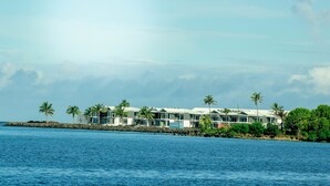 A beachfront hotel with multiple-story buildings, palm trees, and a rocky shoreline. - Ulalei Lodge (Apia)