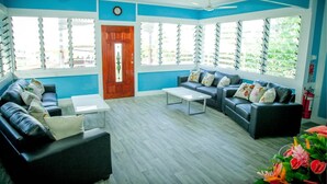 A modern living room with two sofas, a coffee table, and large windows with shutters. - Ulalei Lodge (Apia)