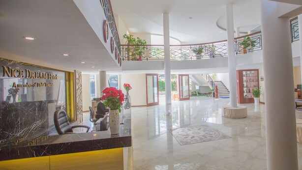 Vestíbulo de hotel con una recepción, una escalera y varios niveles.