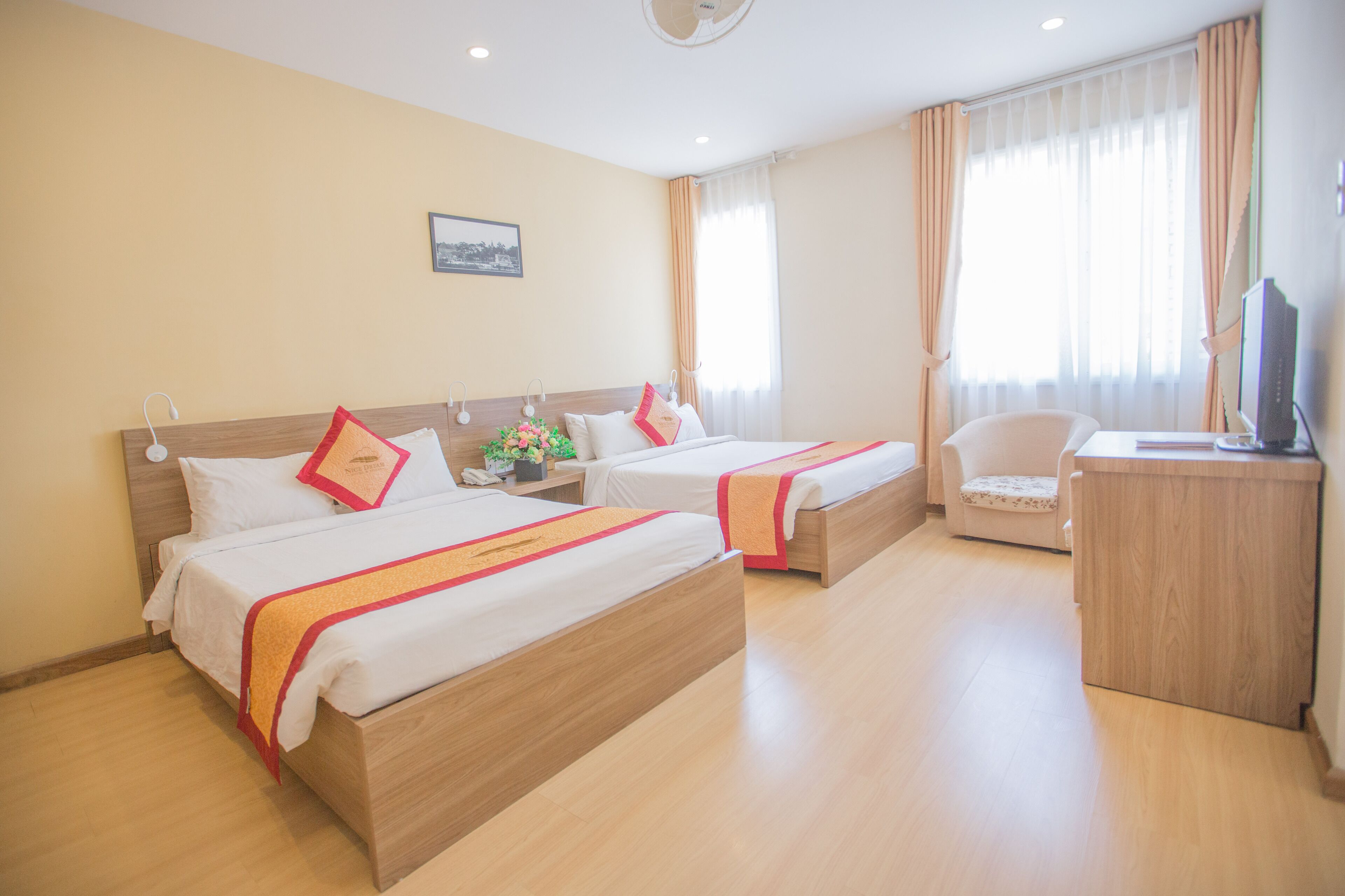 A hotel room with two beds, a desk, a chair, and a television.