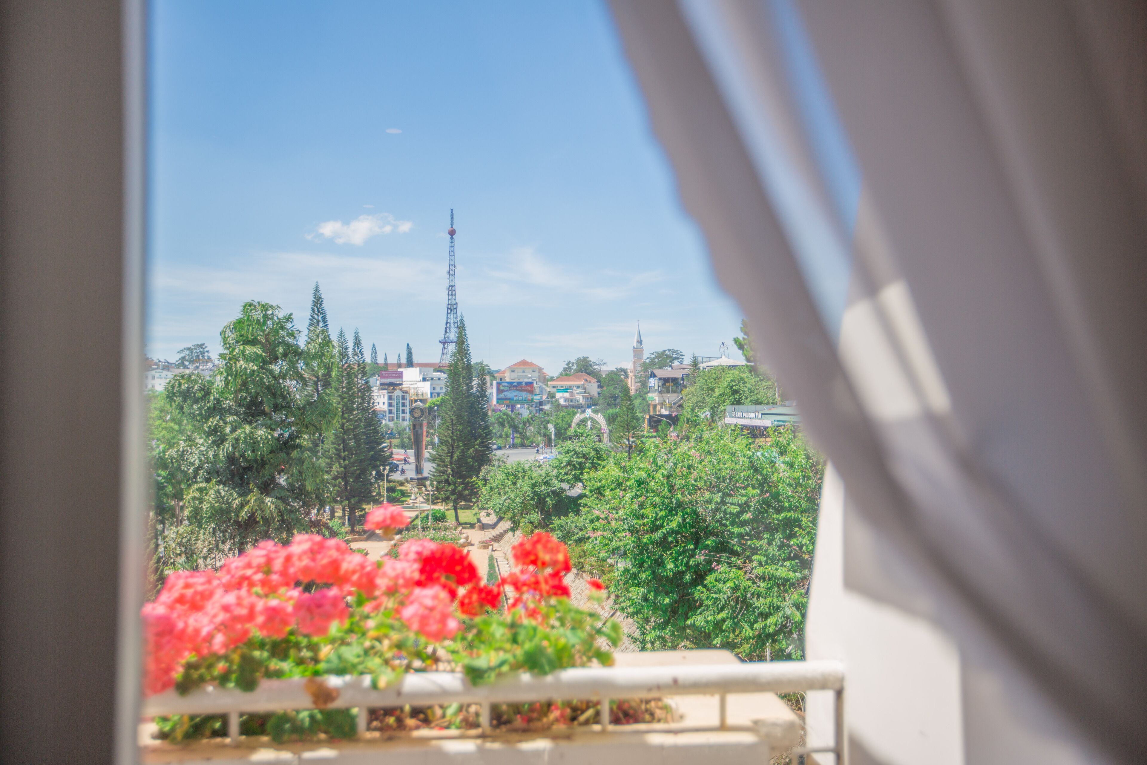 A balcony with a view of a cityscape, including a tall tower and various buildings.