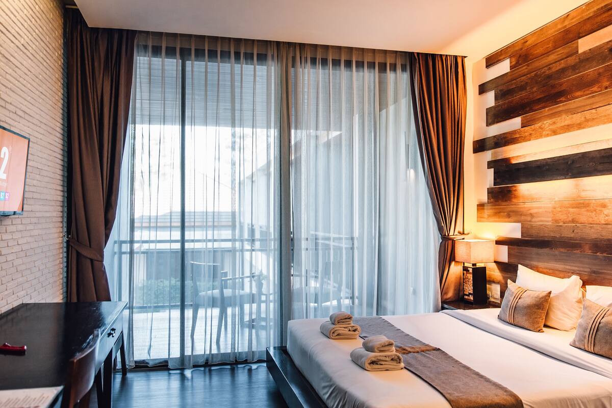 A hotel room with a large bed, a TV on the wall, and a wooden headboard.