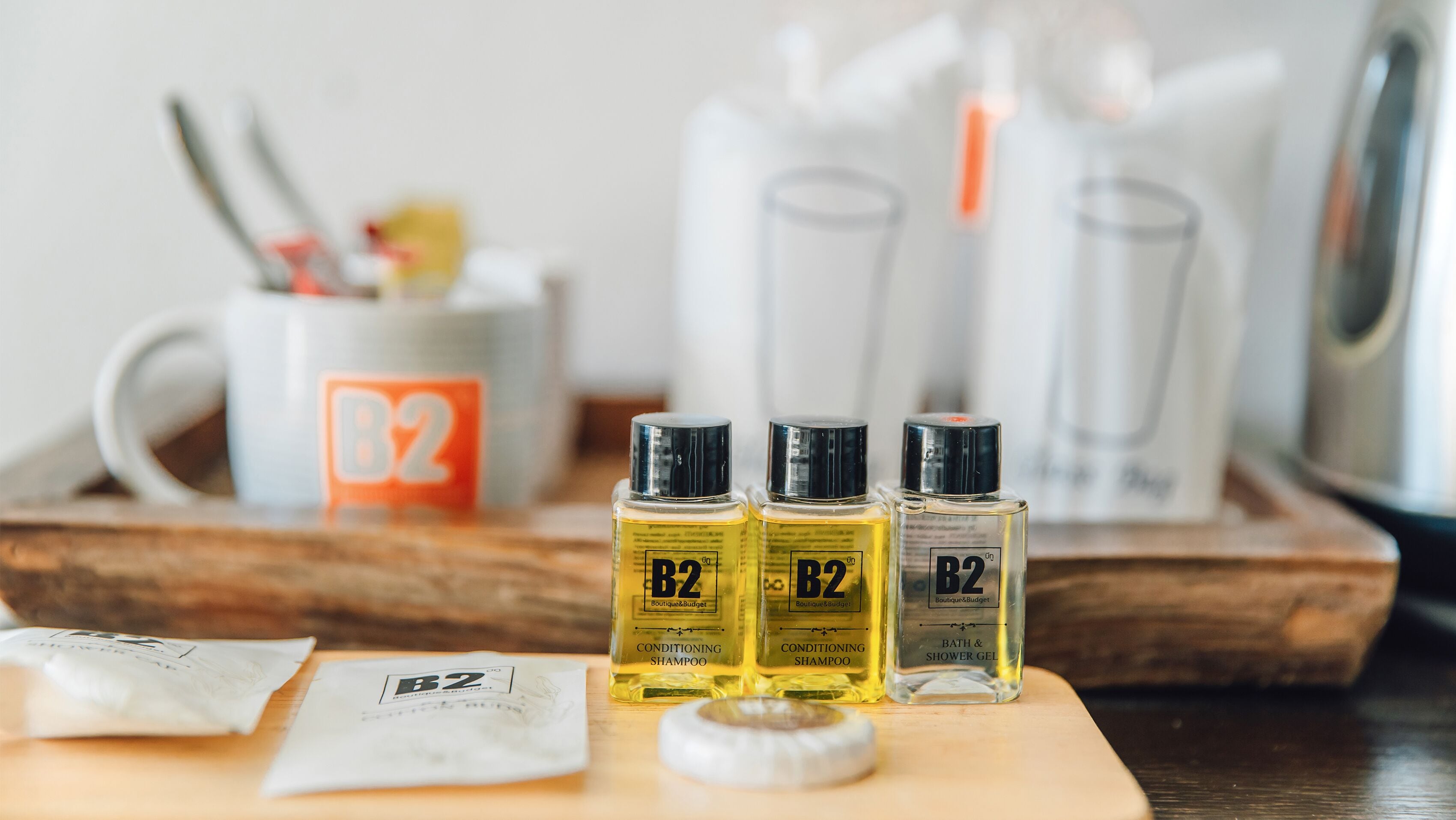 Three bottles of B2 conditioning shampoo and a bottle of B2 bath & shower gel on a wooden tray.