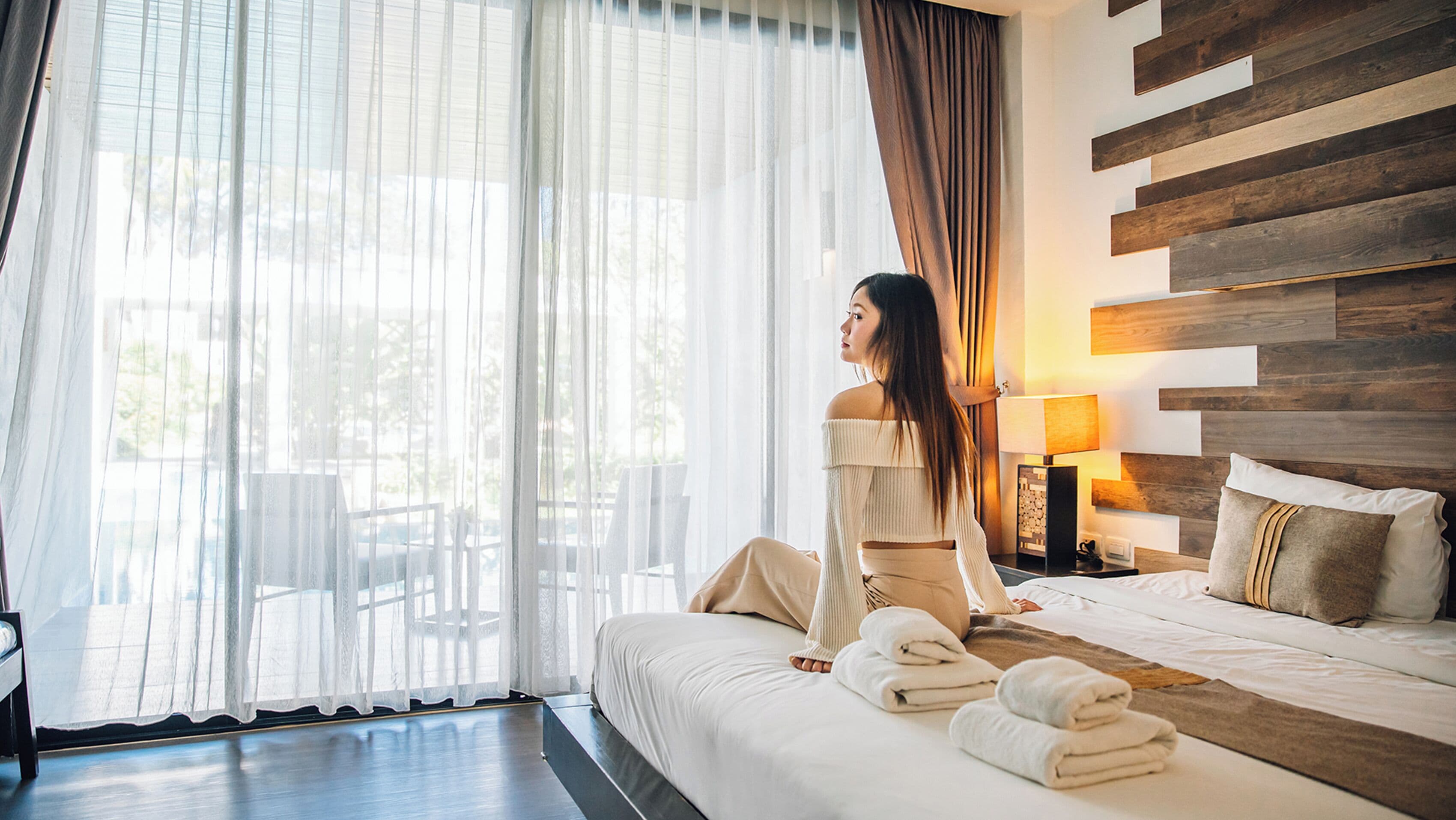 A hotel room with a large bed, a sitting area with a view, and a wooden wall panel.