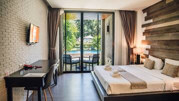 Een hotelkamer met een bed, een bureau en uitzicht op een buitenzwembad.