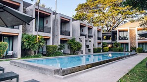 Um edifício moderno com piscina, área de estar externa e vegetação.