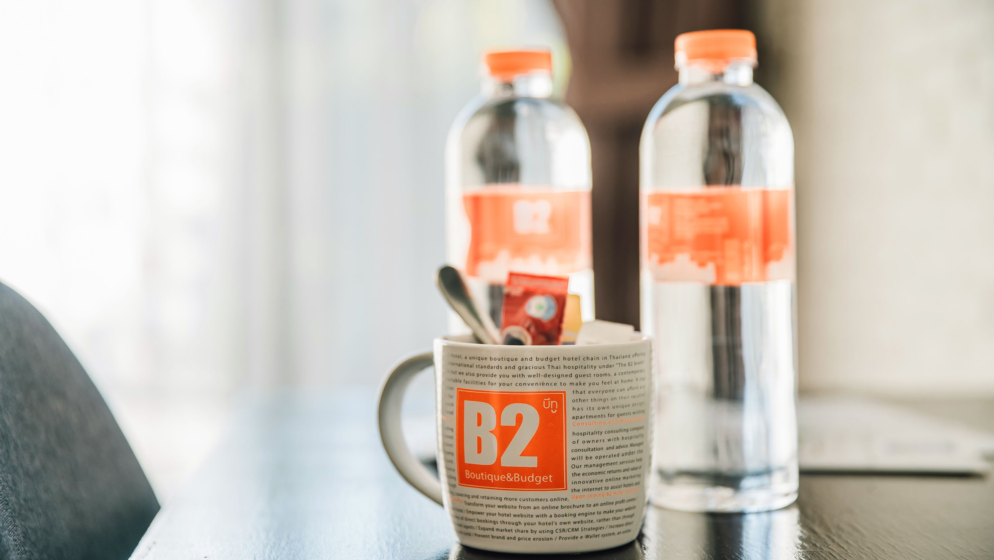 Une brochure présentant l’hôtel B2 Boutique & Budget, posée sur une table avec deux bouteilles d’eau.