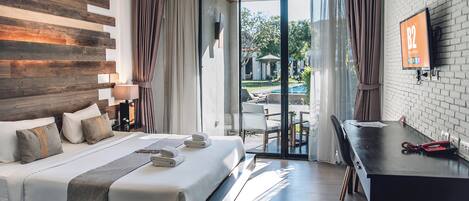 A hotel room with a bed, a desk, a TV, and a view of the outdoors.