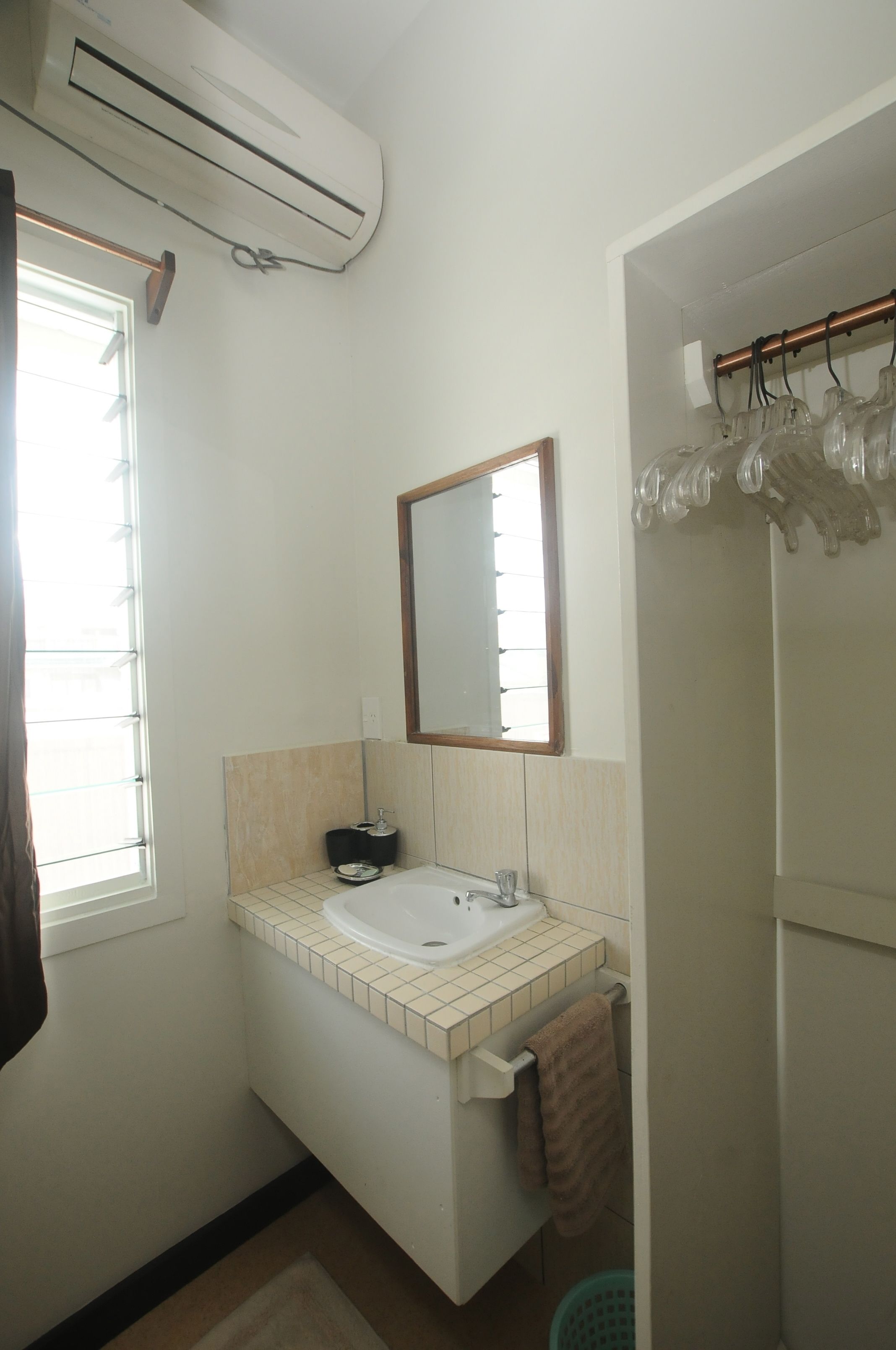 Een badkamer met een wastafel, spiegel en raam.