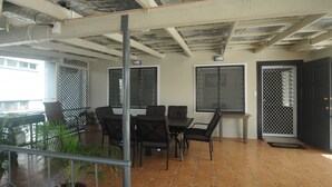 A terrace with a table and chairs, a metal railing, and potted plants. - Talofa Inn (Apia)