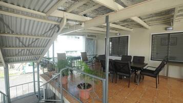 Un espacio al aire libre cubierto con una escalera, una mesa con sillas y plantas en macetas.