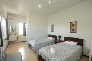 A hotel room with two beds, a bathroom, and a small sitting area. - Talofa Inn (Apia)