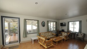 A living room with a sofa, chairs, a coffee table, and a television. - Talofa Inn (Apia)