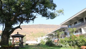 A hotel with a large tree, a gazebo, and a well-maintained lawn. - Club Mahindra Hatgad (Nashik)