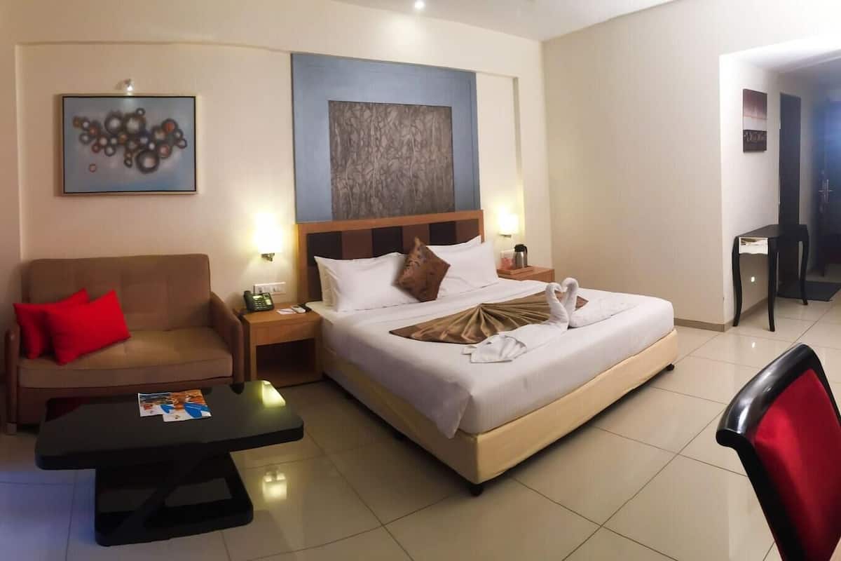 A hotel room with a bed, a sofa, a coffee table, and a chair.