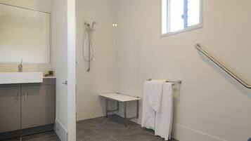 Un baño con ducha, lavamanos, espejo y ventana.