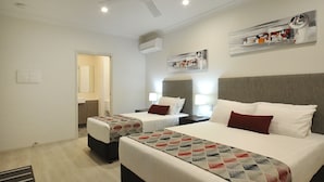 A hotel room with two beds, a ceiling fan, a mounted air conditioner, and a wall-mounted artwork. - Northpoint Motel (Harlaxton)