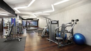 A gym with various exercise equipment, wooden flooring, and a large mirror. - StayCentral - NGV Arts Centre Retreat (Southbank)