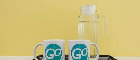 Deux tasses blanches ornées d’un logo turquoise et du mot « HÔTELS », posées sur un plateau.