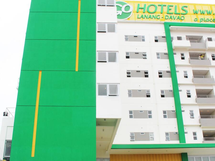 A multi-story hotel with a prominent green and yellow facade, featuring the Go Hotels logo and a website address.