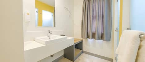 A modern bathroom with a white sink, mirror, and shower curtain.