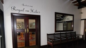 Un área de recepción con un banco de madera, un doble acceso con paneles de vidrio y un cartel en la pared que dice "Royal on Heber".