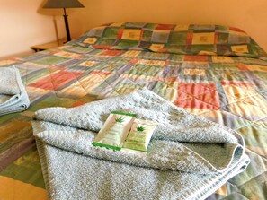 Una cama con un colcha colorida, una toalla doblada y una barra limpiadora Lanovera sobre la cama.
