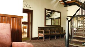 Un vestíbulo de hotel con un banco de madera, un espejo grande y una escalera.