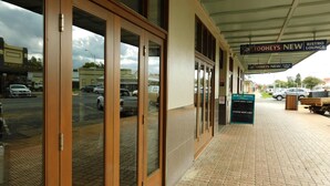 Entrada de un hotel con puertas de vidrio, un cartel que dice 'Tooheys New Bistro Lounge' y un letrero del 'Royal Hotel'.
