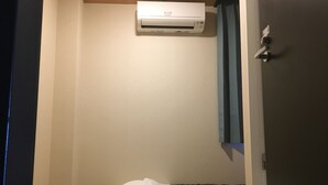 A hotel room with a bed, a wall-mounted air conditioner, and a door with a handle. - Peace International hotel Ichinomiya (Ichinomiya)