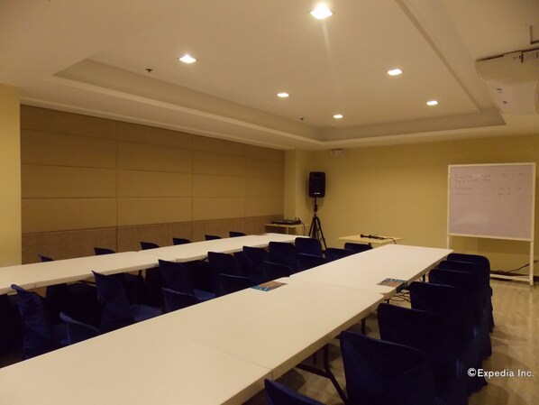 A conference room with a long table, chairs, a whiteboard, and a speaker on a tripod. - Madison Hotel PHL (Iloilo)