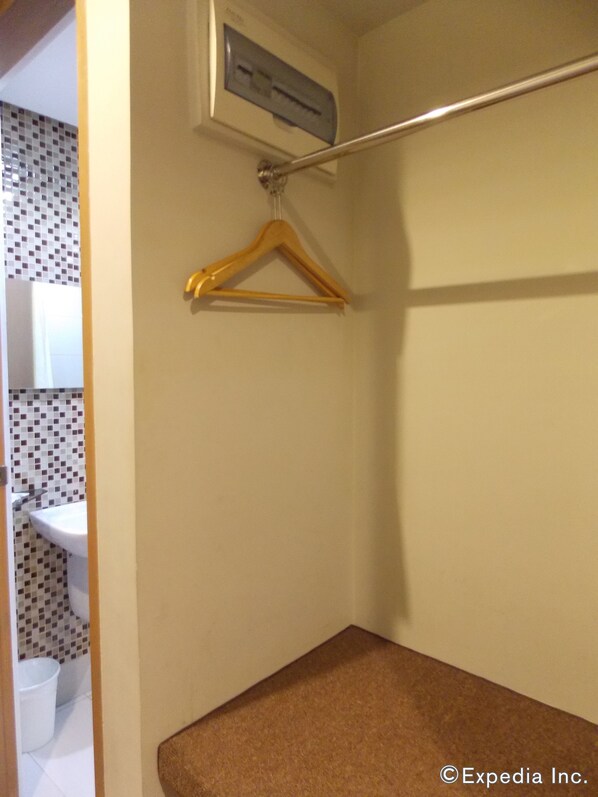 A bathroom with a white sink, a toilet, a shower area, and a towel rack with a single towel. - Madison Hotel PHL (Iloilo)