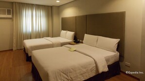 Habitación de hotel con dos camas, una mesita de noche y una ventana con cortinas.