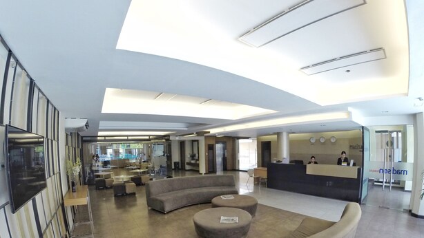 Un vestíbulo amplio con una zona de estar curvilínea, un mostrador de recepción y un televisor de pantalla plana grande montado en la pared.