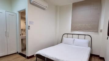 A bedroom with a bed, wardrobe, and an air conditioning unit.