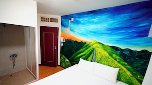 Ein Hotelzimmer mit Bett, Dusche und einem Wandbild einer Berglandschaft.