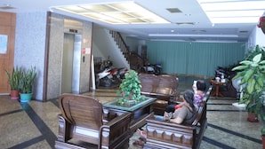 A spacious lobby with a high ceiling, a staircase, and a seating area with wooden furniture. - Chantai Hotel (Hualien City)
