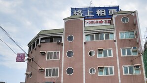 A multi-story building with a prominent sign for Chan Tai Hotel. The building features a brick facade with multiple windows, some with air conditioning units. There are various signs and banners, including one for a hotel and another for a business. - Chantai Hotel (Hualien City)