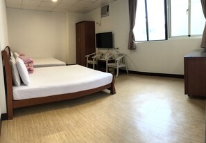 A hotel room with a wooden bed, a small desk with a chair, a television, and a wardrobe. - Chantai Hotel (Hualien City)