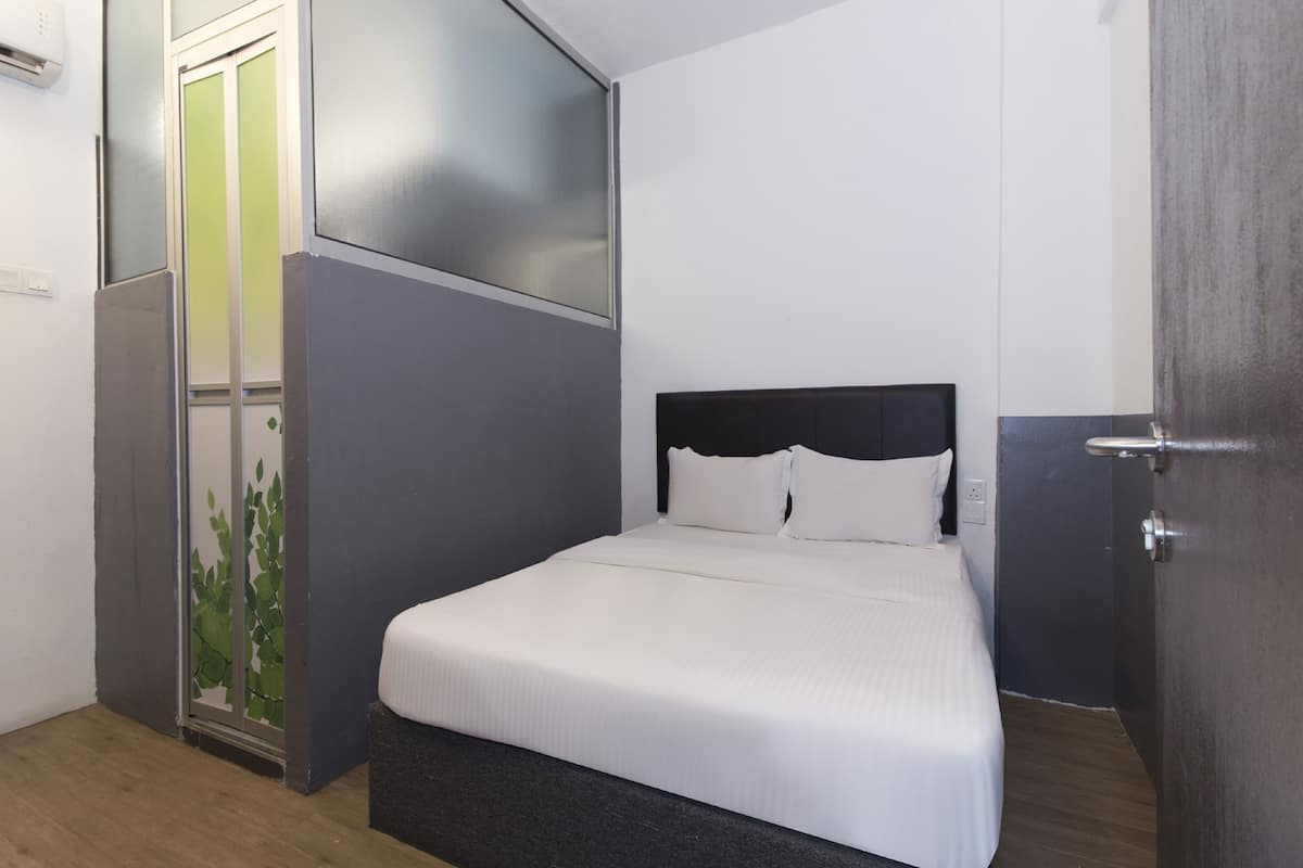 A bedroom with a bed, a door, and a wall with a window.